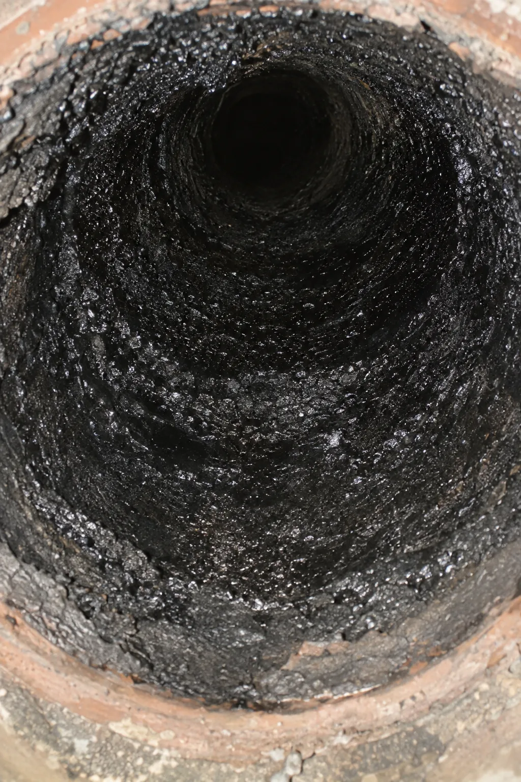 Shiny black Stage 3 creosote glaze coating the inside of a clay flue liner